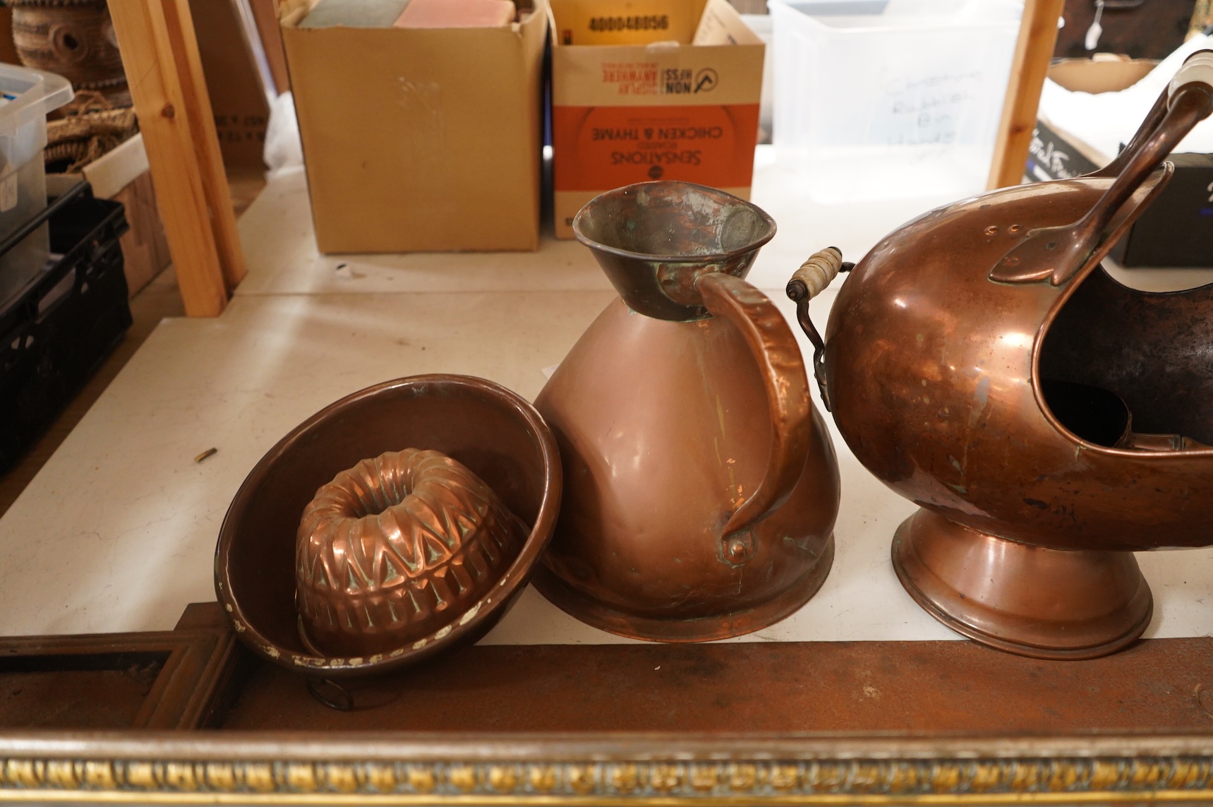 A collection of metalware to include a steel and brass fender, a helmet scuttle, 19th century jelly mould and a harvest jug